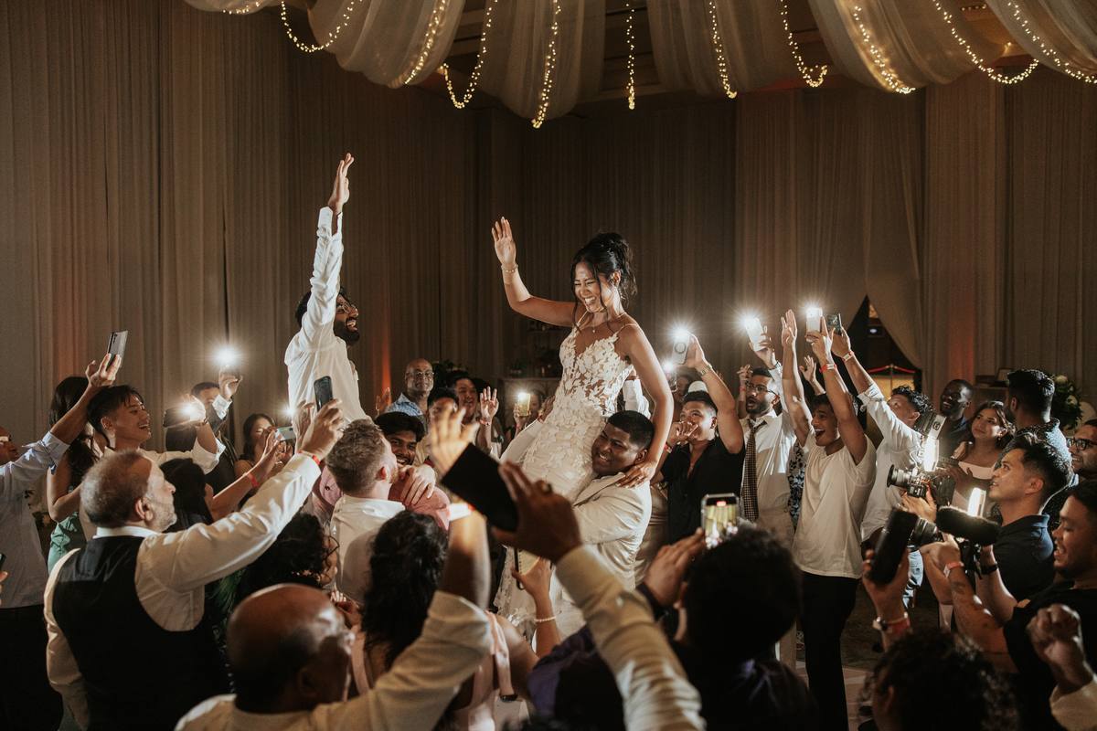 Bride and groom exchanging vows in a sunlit ceremony surrounded by family and friends