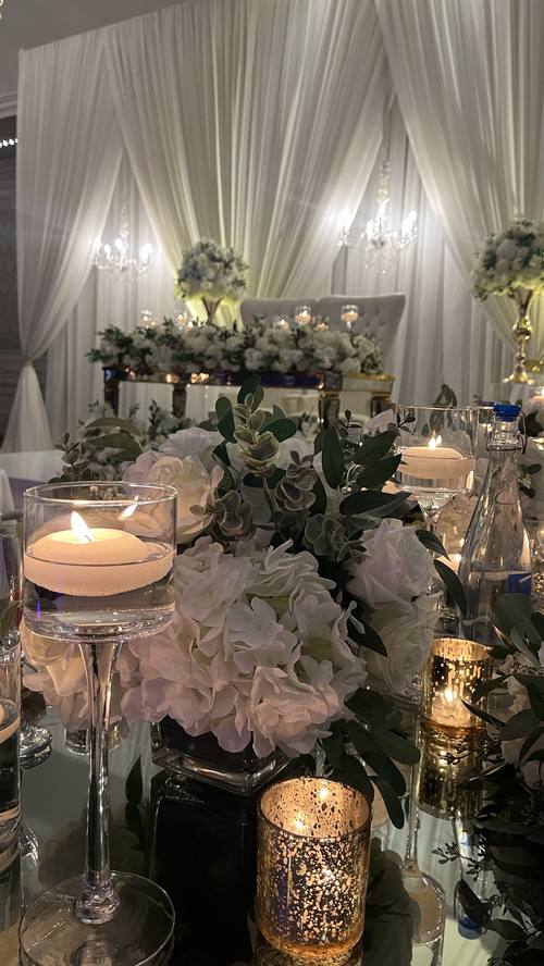 Long banquet table with cascading floral runner and taper candles at a vineyard wedding reception